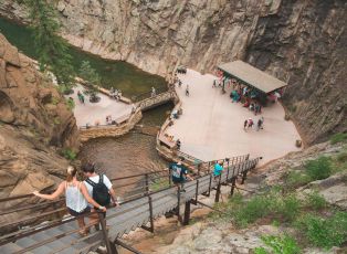 People Sitting On A Wooden Bridge Over A River